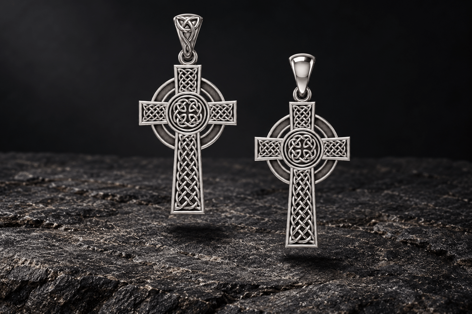 Front and back of a reversible sterling silver Celtic cross pendant with a ringed outline and interlaced knotwork, displayed above dark stone.