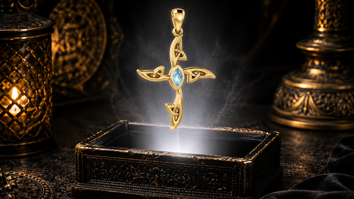 Solid 14K gold contemporary Celtic cross pendant with a blue topaz gemstone floating above an ornate jewelry box in a refined dark luxury setting with warm candlelight, cinematic lighting, and a mystical atmosphere.