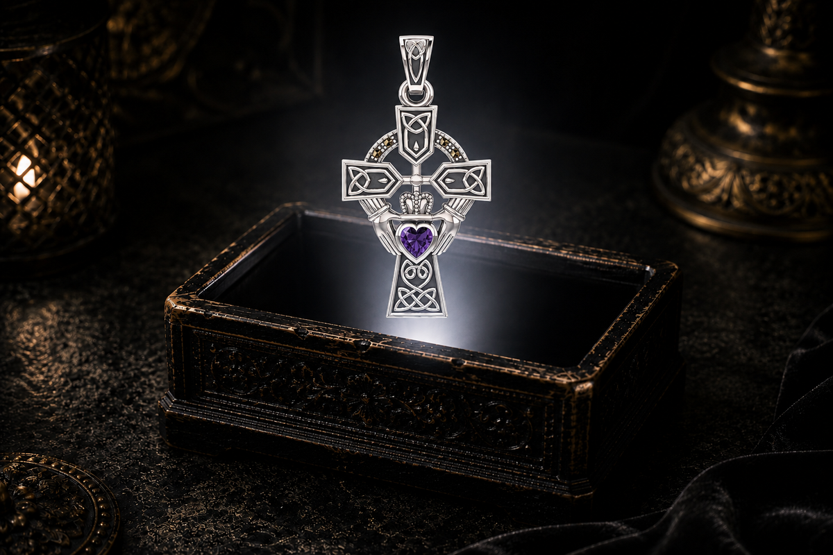 14K white gold Celtic Cross pendant with a Claddagh design, amethyst heart, and marcasite accents floating above an antique jewelry box.