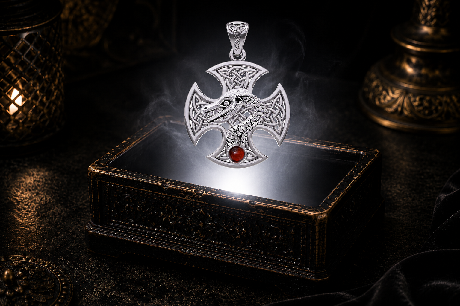 Handcrafted Celtic Dragon Cross pendant crafted in 14K White Gold with a genuine garnet gemstone floating above an antique treasure box surrounded by mist and warm golden candlelight.