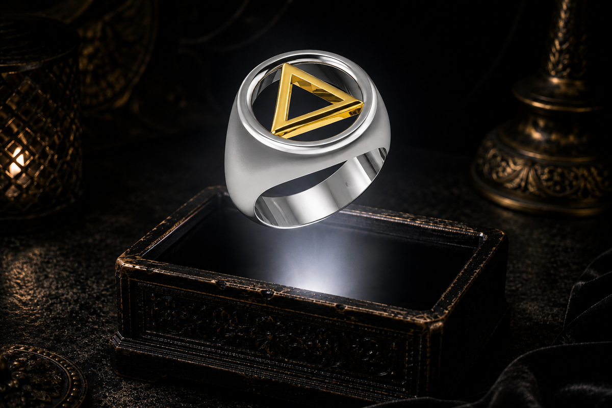 14K white gold recovery ring with a raised yellow gold circle-and-triangle symbol floating above an antique jewelry box in a neutral beam of light