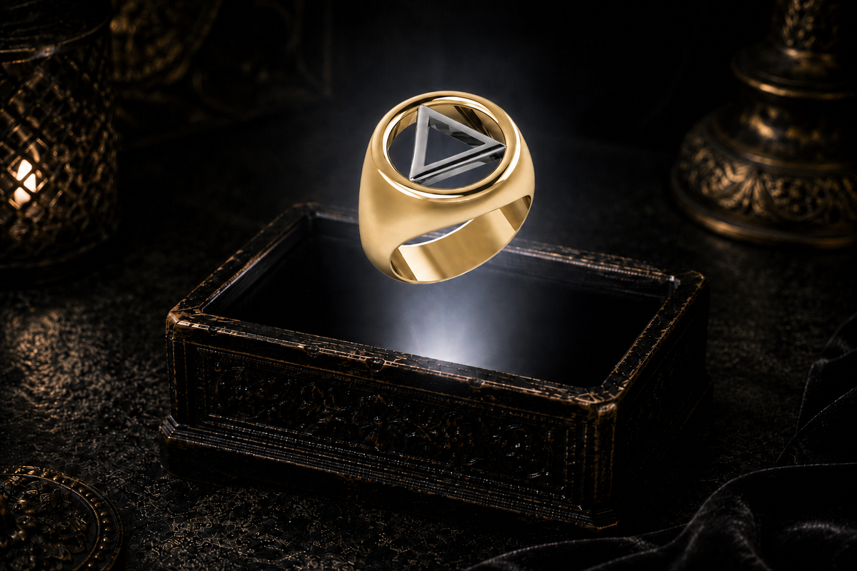 Gold Recovery ring with a white gold triangle inside an open circular frame, floating above an antique jewelry box.