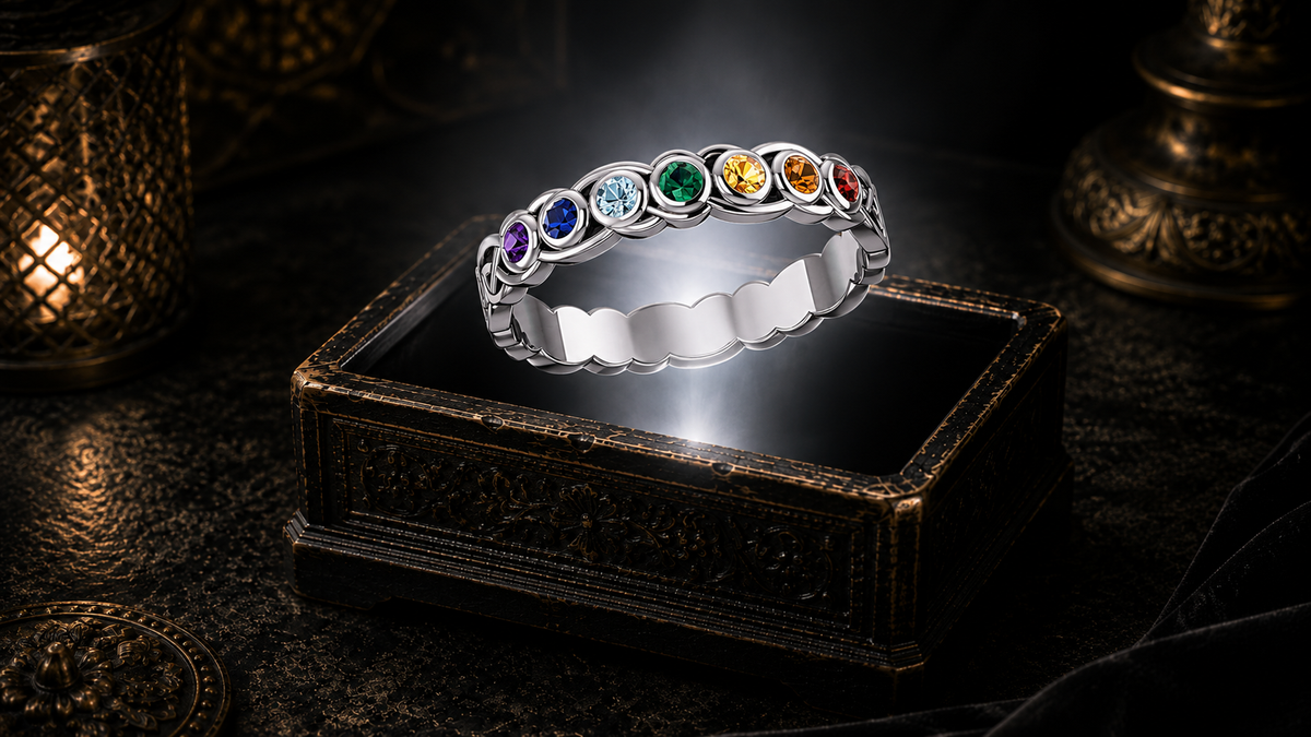 Sterling silver Celtic chakra band ring featuring seven colorful gemstones and intricate Celtic knotwork floating above an ornate jewelry box in a dark cinematic luxury setting illuminated by mystical light.