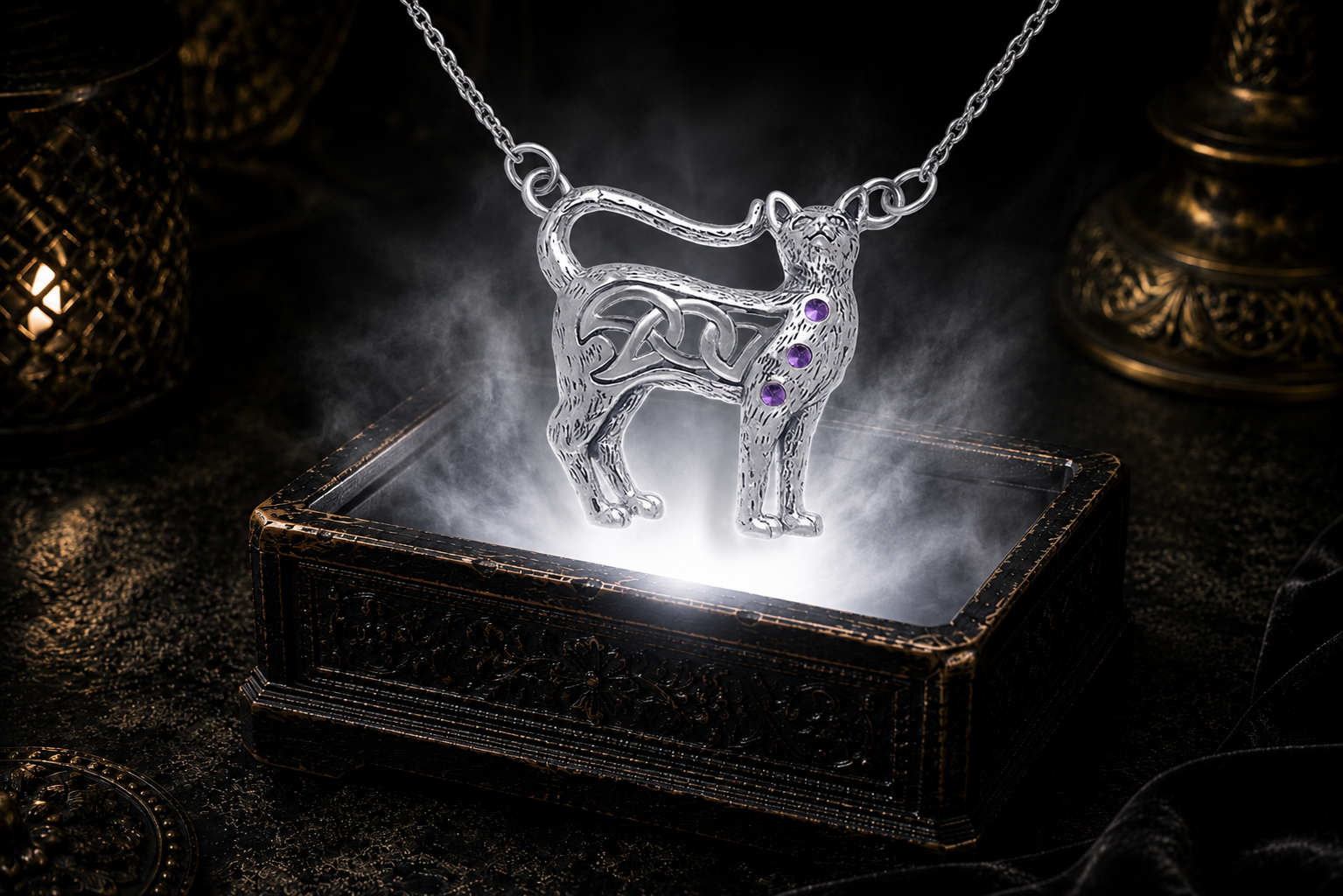 Sterling silver Celtic cat necklace with amethyst gemstone accents illuminated above an ornate jewelry chest surrounded by soft glowing light