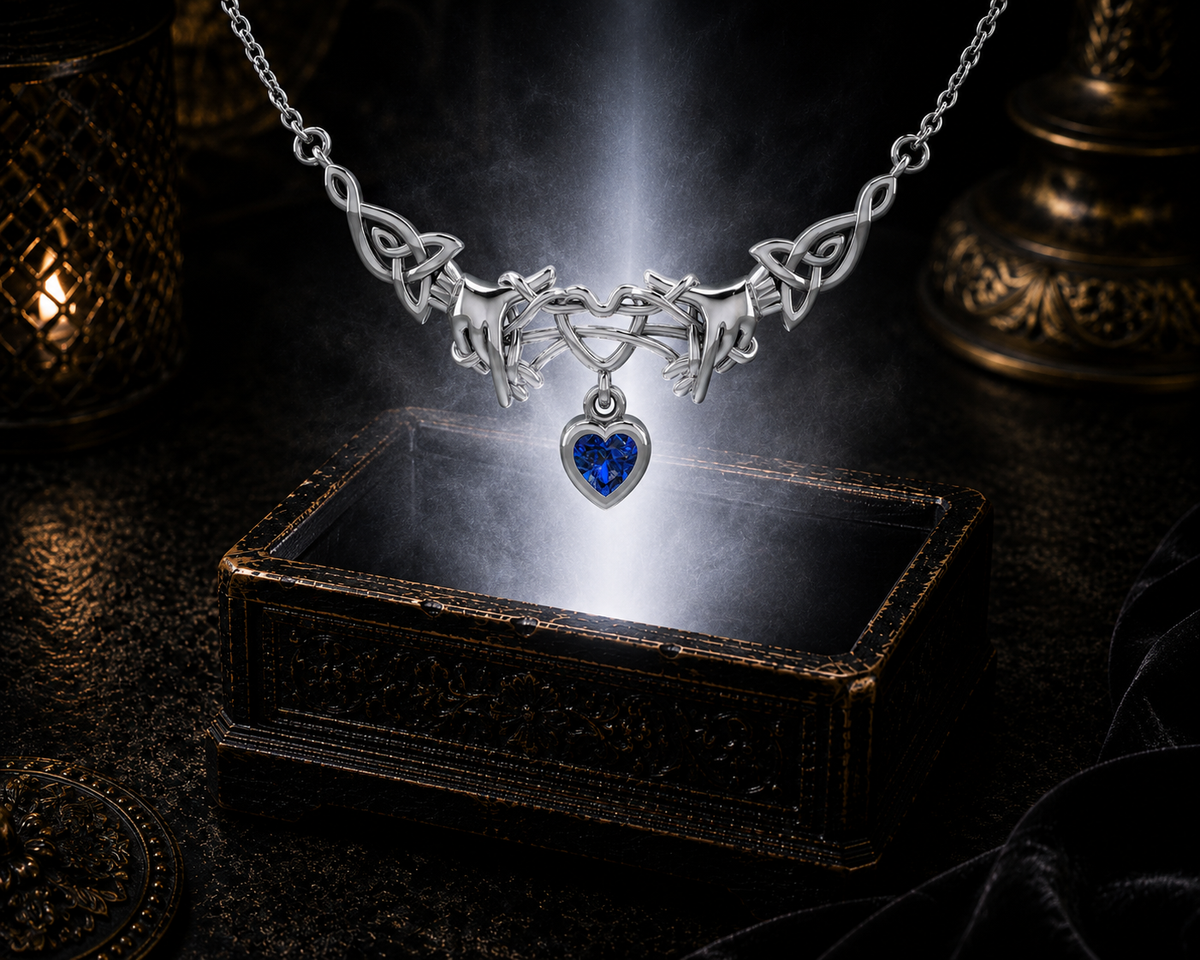 Sterling silver Ayatori Celtic heart necklace with sapphire gemstone floating above an ornate jewelry box surrounded by brilliant blue light in a dramatic luxury environment.