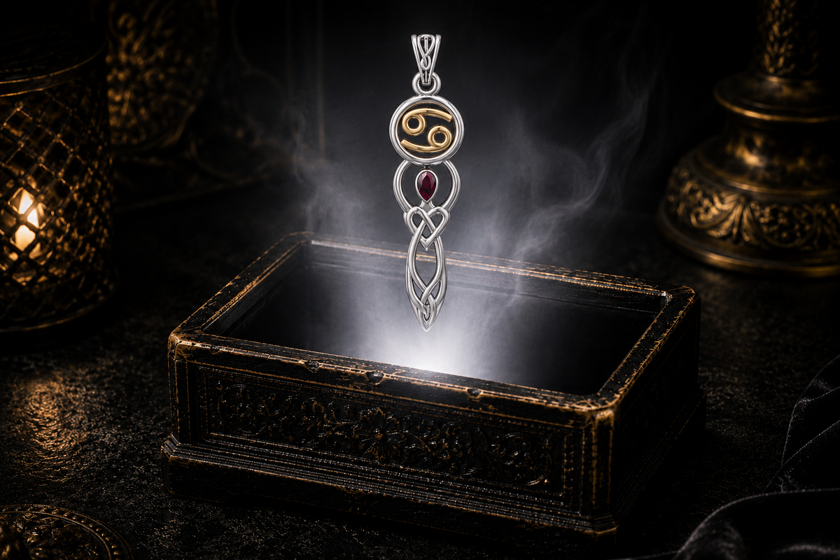Sterling silver Cancer birthstone pendant with ruby, gold accents, and Celtic goddess symbolism showcased above an antique jewelry box surrounded by mystical light and shadow.