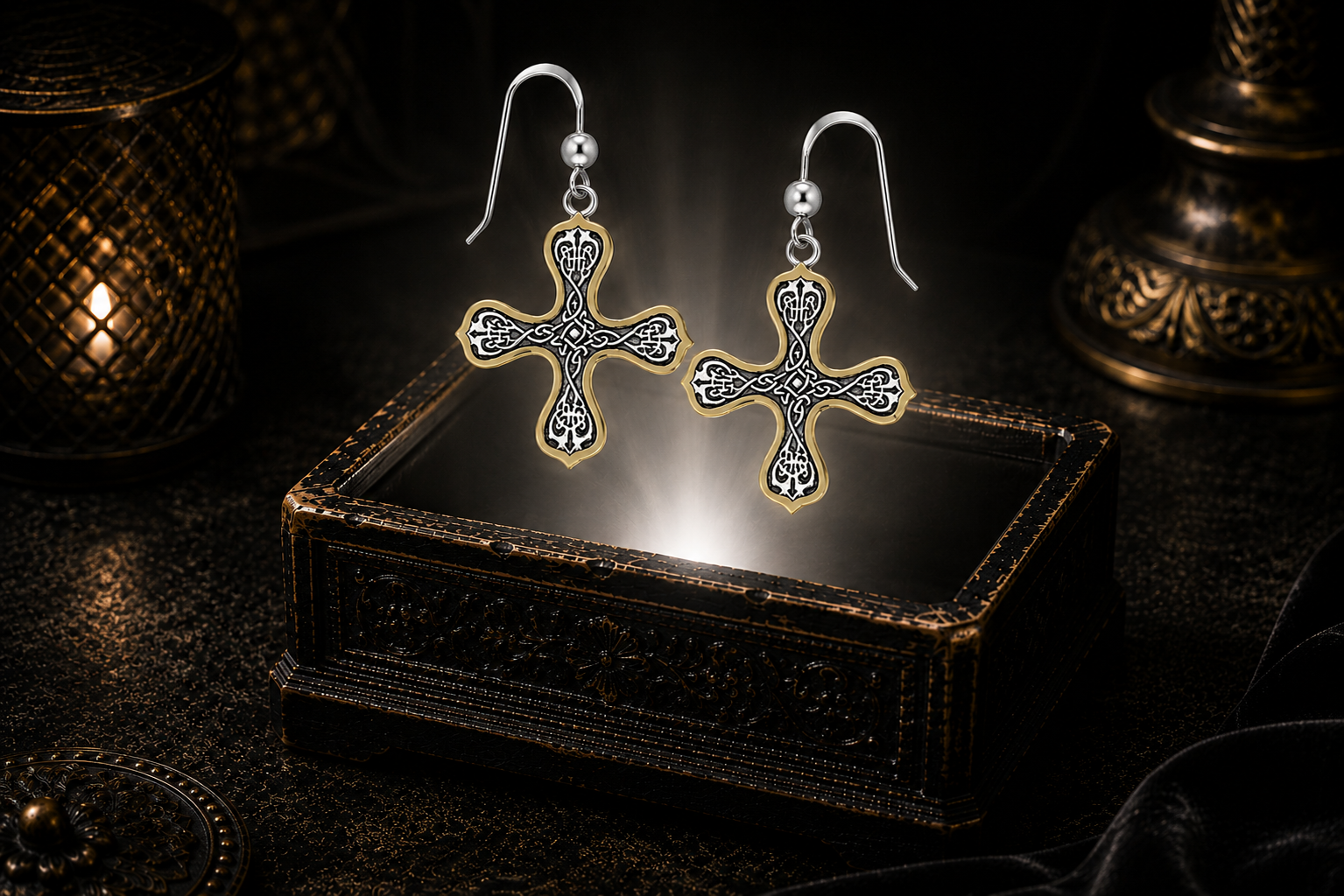 Sterling silver Celtic budded cross earrings with 14K gold accents floating above a glowing ornate jewelry box in a dark luxury setting