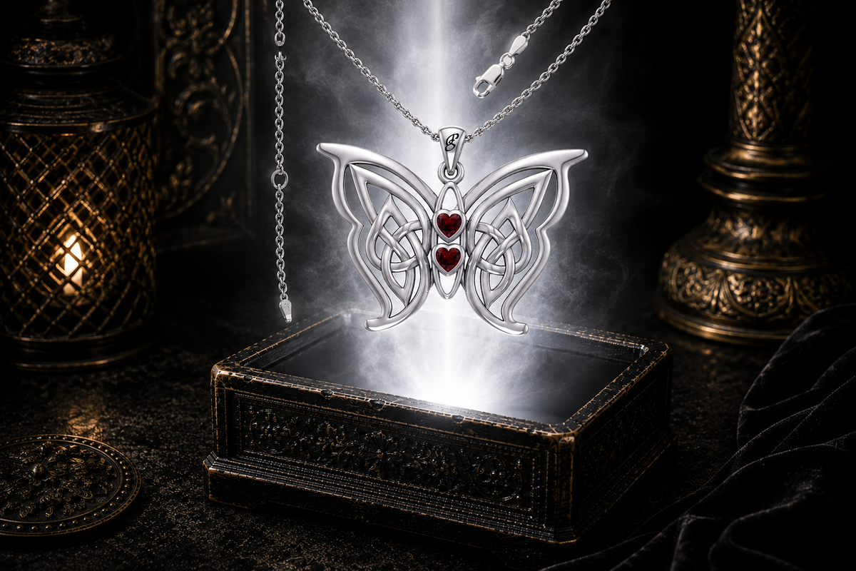 Sterling silver Celtic butterfly pendant with twin garnet heart gemstones floating above an ornate dark jewelry box surrounded by luminous white light and drifting mist in a cinematic luxury setting.