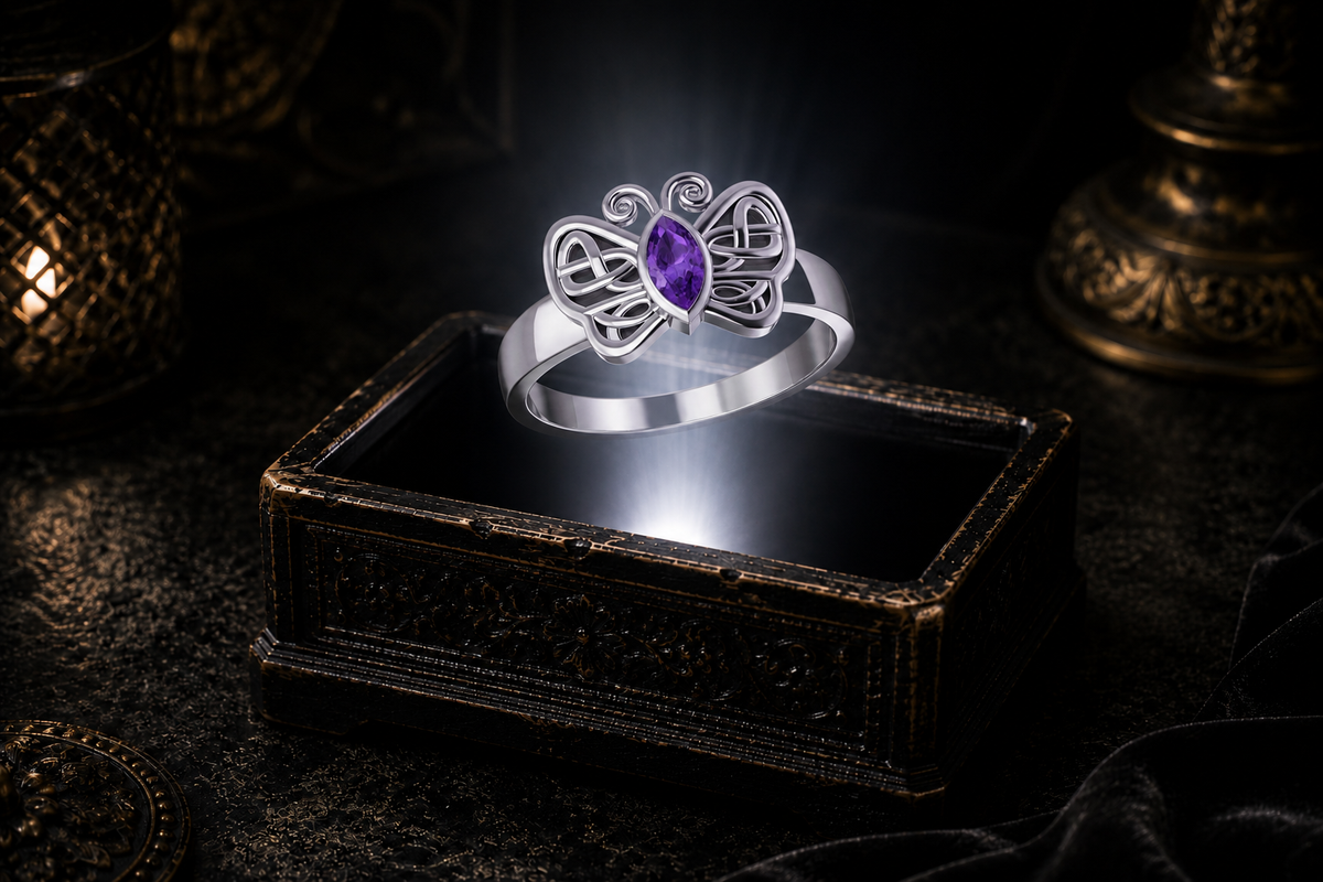 Sterling silver Celtic butterfly ring with a marquise-cut amethyst gemstone suspended above an antique jewelry box within a neutral white beam of light.