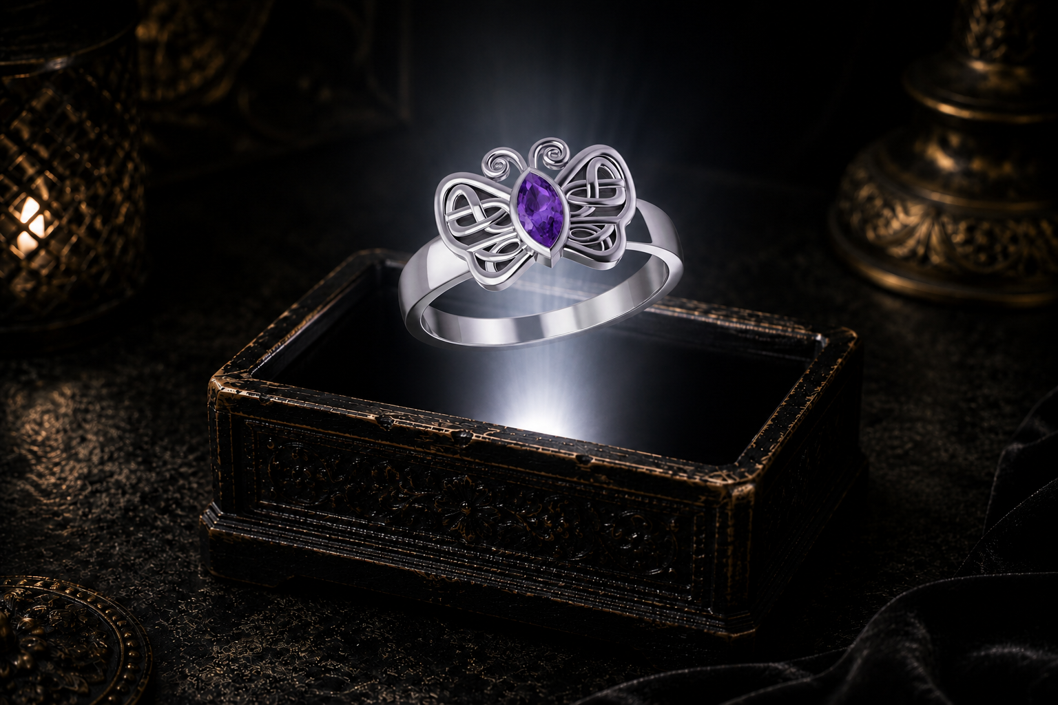Celtic butterfly ring in sterling silver featuring a marquise-cut blue topaz gemstone hovering over an ornate keepsake box illuminated by warm candlelight.