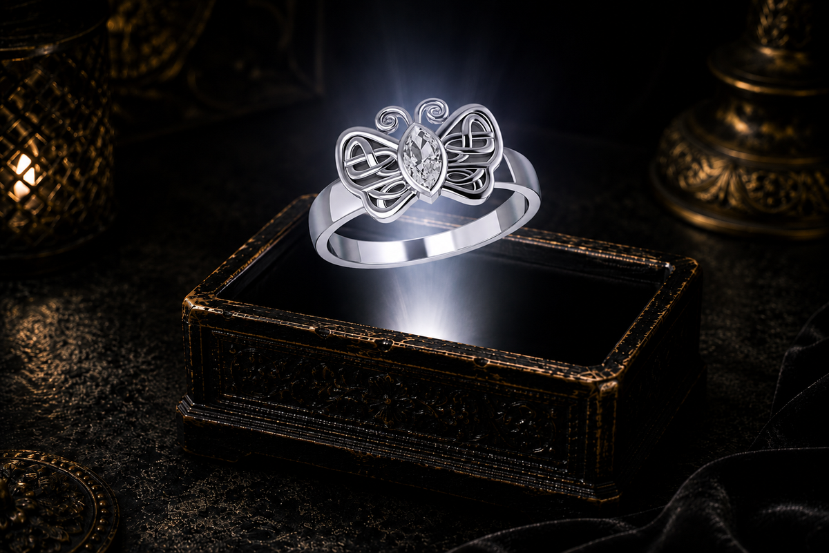 Celtic butterfly ring crafted in sterling silver with a marquise-cut clear cubic zirconia centerpiece floating above an antique jewelry box against a refined dark backdrop.