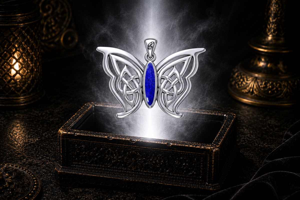 Sterling silver Celtic butterfly pendant with lapis gemstone inlay floating above an ornate dark jewelry box surrounded by luminous white light in a cinematic luxury setting.