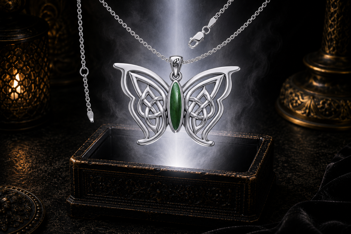 Sterling silver Celtic butterfly pendant with chain and malachite gemstone inlay floating above an ornate dark jewelry box surrounded by luminous white light in a cinematic luxury setting.