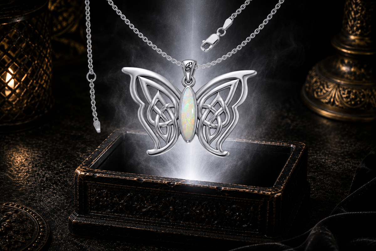 Sterling silver Celtic butterfly pendant with chain and opal gemstone inlay floating above an ornate dark jewelry box surrounded by luminous white light in a cinematic luxury setting.
