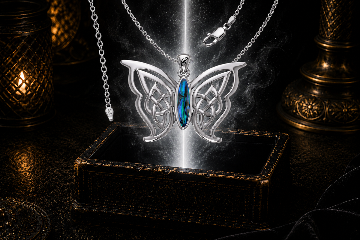 Sterling silver Celtic butterfly pendant with chain and paua shell gemstone inlay floating above an ornate dark jewelry box surrounded by luminous white light in a cinematic luxury setting.