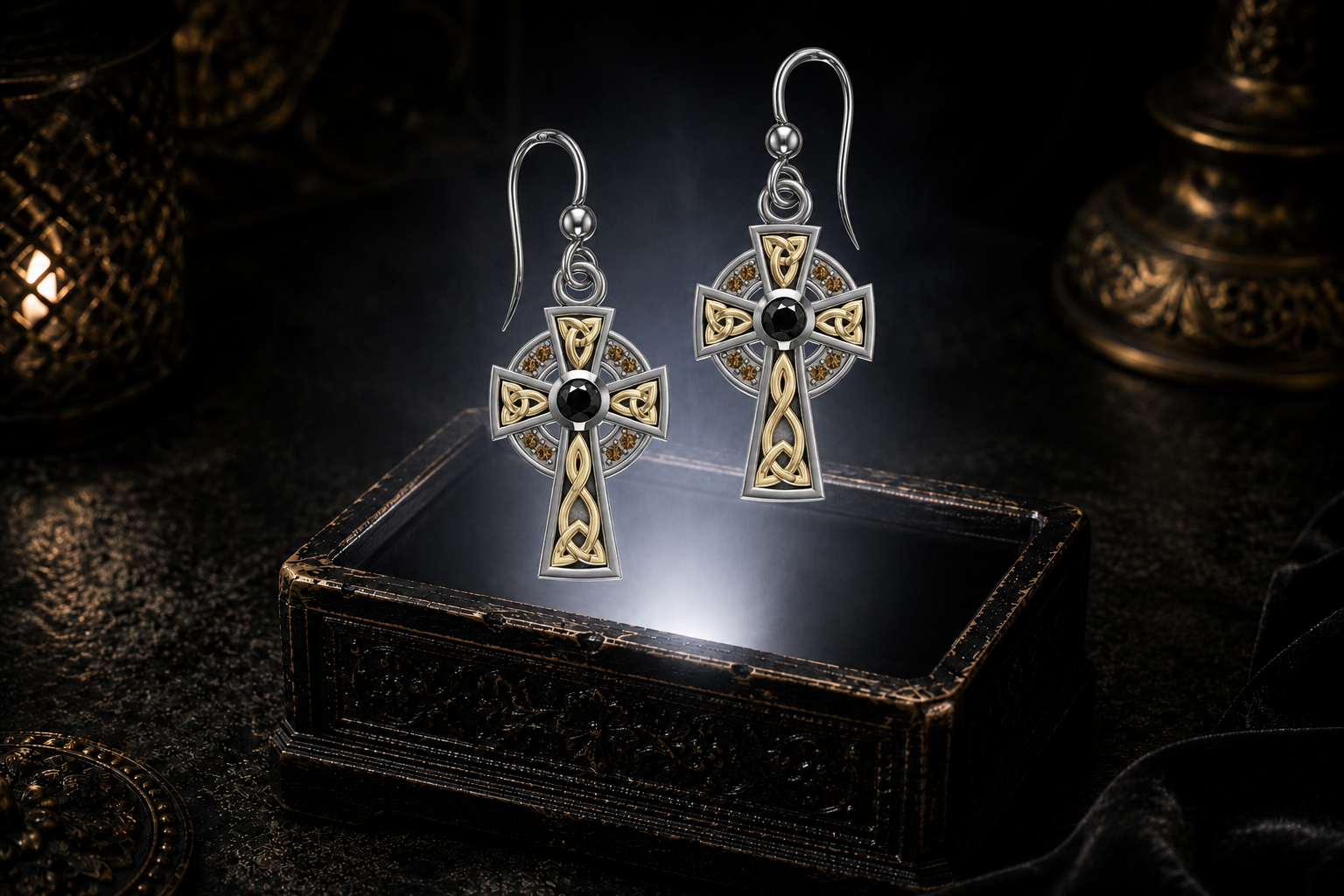 Sterling silver Celtic cross earrings with black and cognac cubic zirconia accents floating above a glowing ornate jewelry box in a dark luxury setting