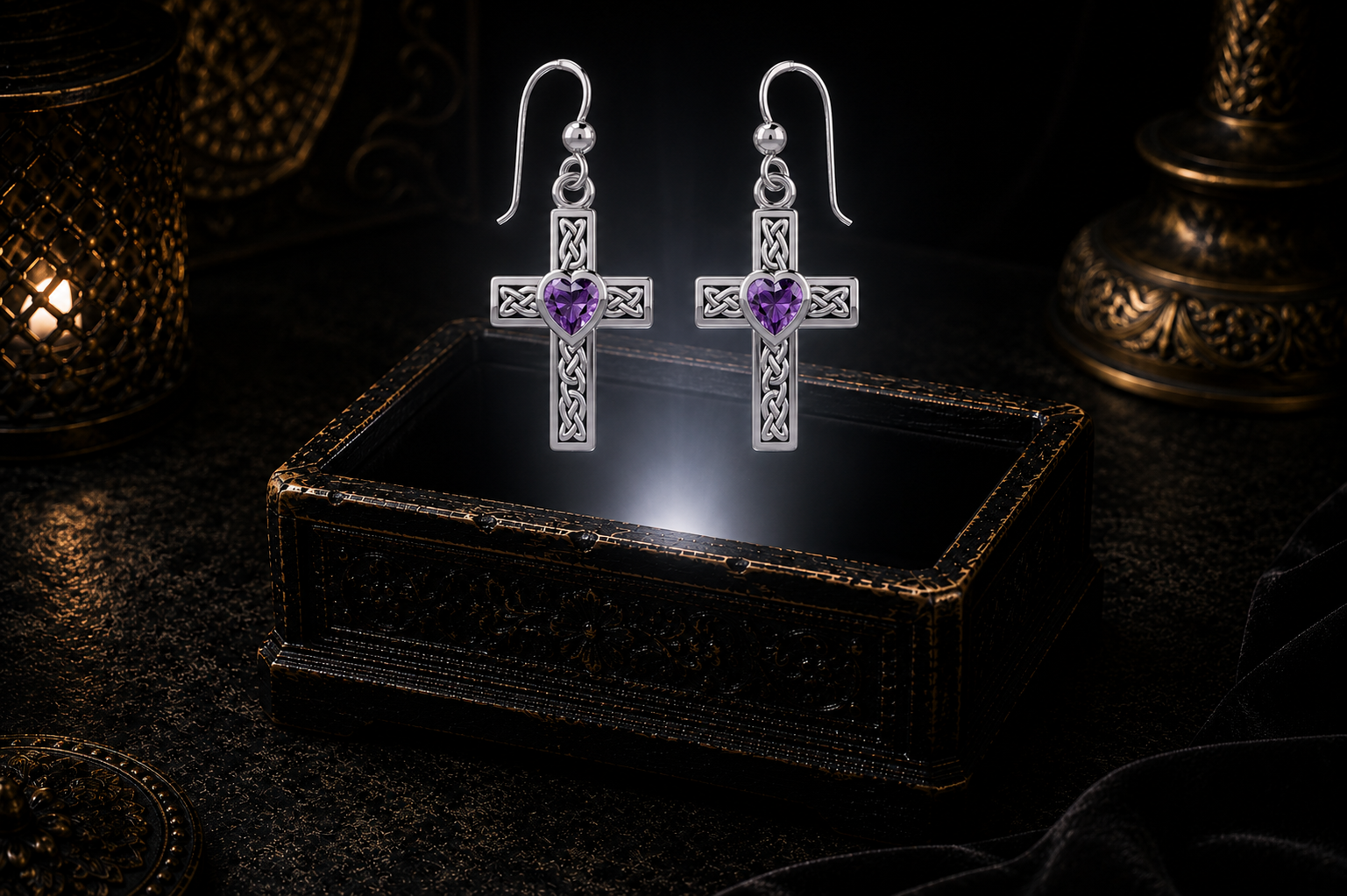 Sterling silver Celtic cross earrings with amethyst heart gemstones floating above a glowing ornate jewelry box in a dark luxury setting