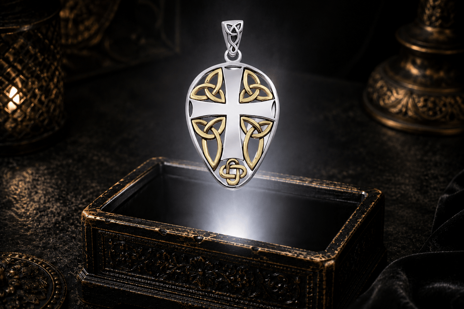 Sterling silver Celtic cross shield pendant with gold knotwork accents suspended above an antique jewelry box in a neutral white beam of light.