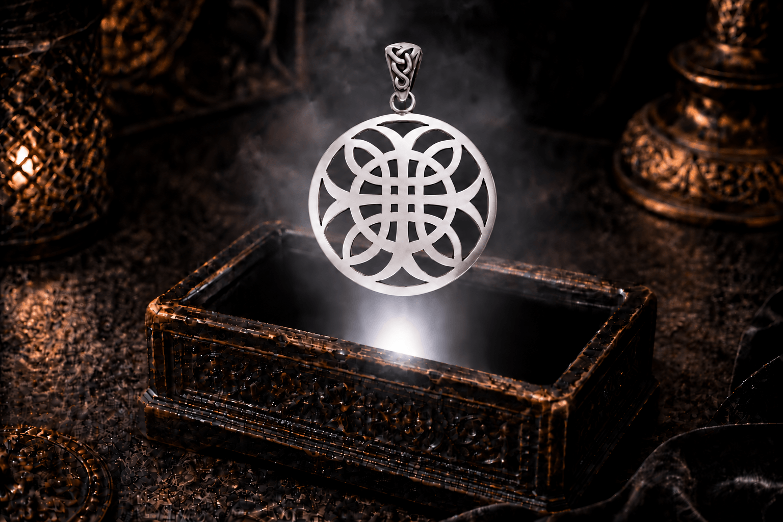 Celtic Cross of Harmony pendant in silver hovering above an ornate dark jewelry box, with white light illuminating its openwork design.