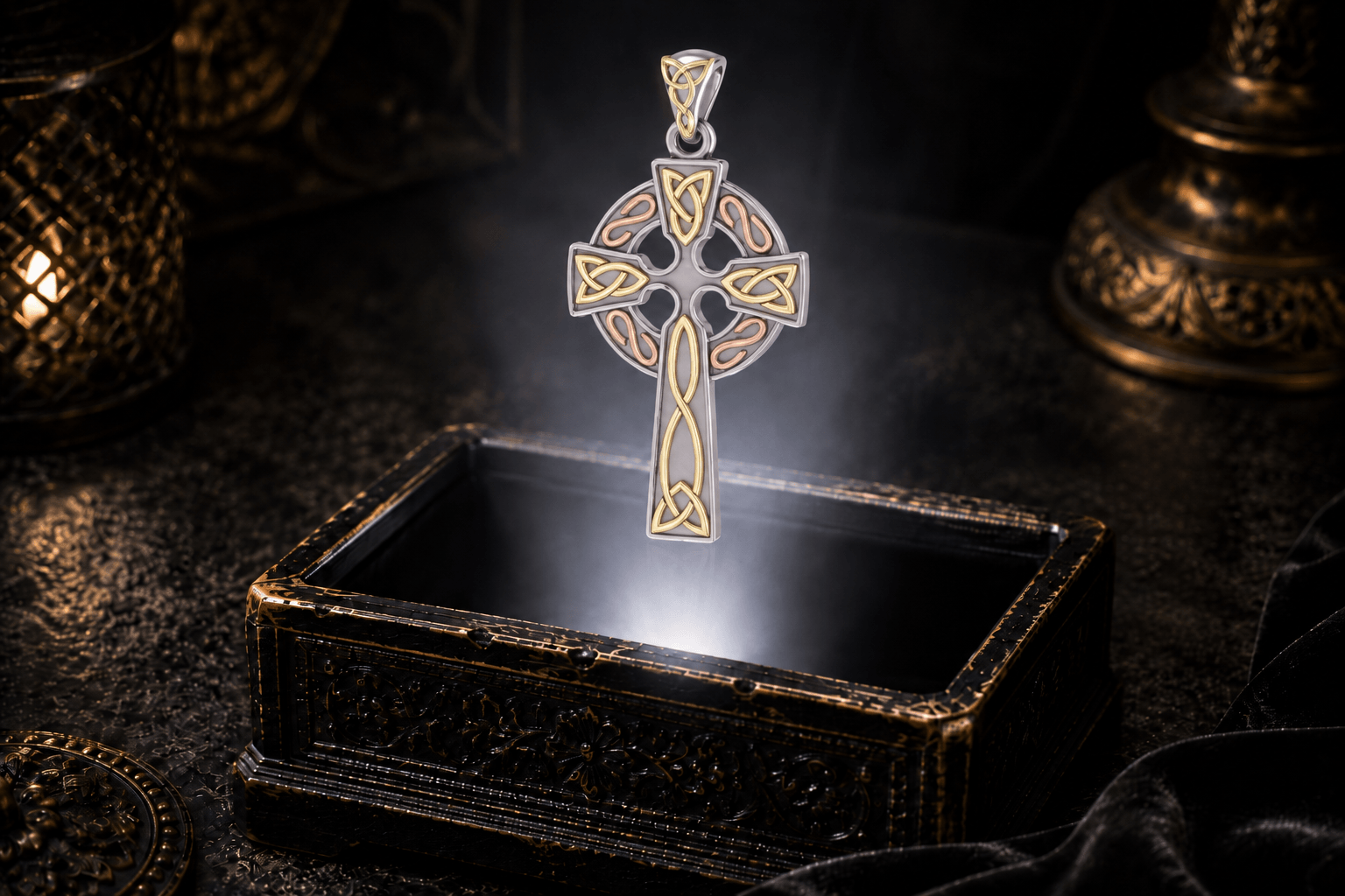 Three-tone Celtic cross pendant hovering above an antique jewelry box with sterling silver, yellow gold, and rose gold details