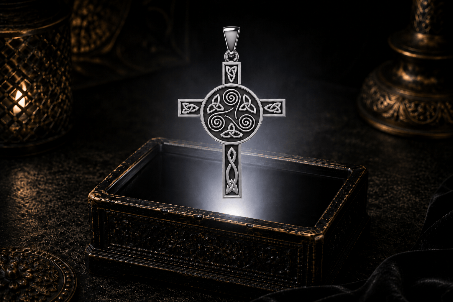 Sterling silver Celtic cross pendant with a central triskele and triangular knotwork hovering above an antique jewelry box.
