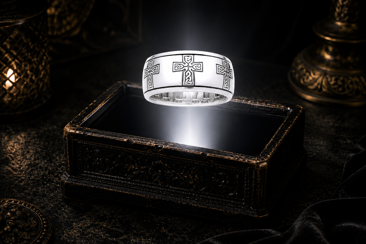 Sterling silver Celtic cross ring engraved with intricate Celtic knotwork floating above an antique jewelry box in a dramatic beam of light.