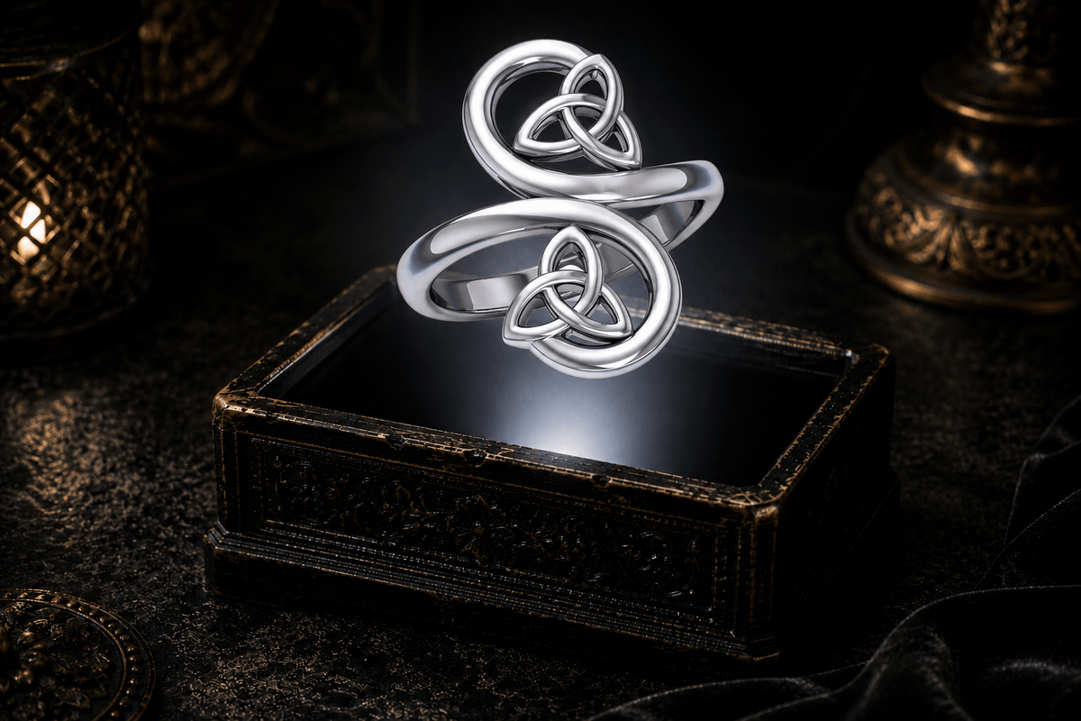 Sterling silver double Trinity knot ring floating above an antique jewelry box within a neutral white beam of light.