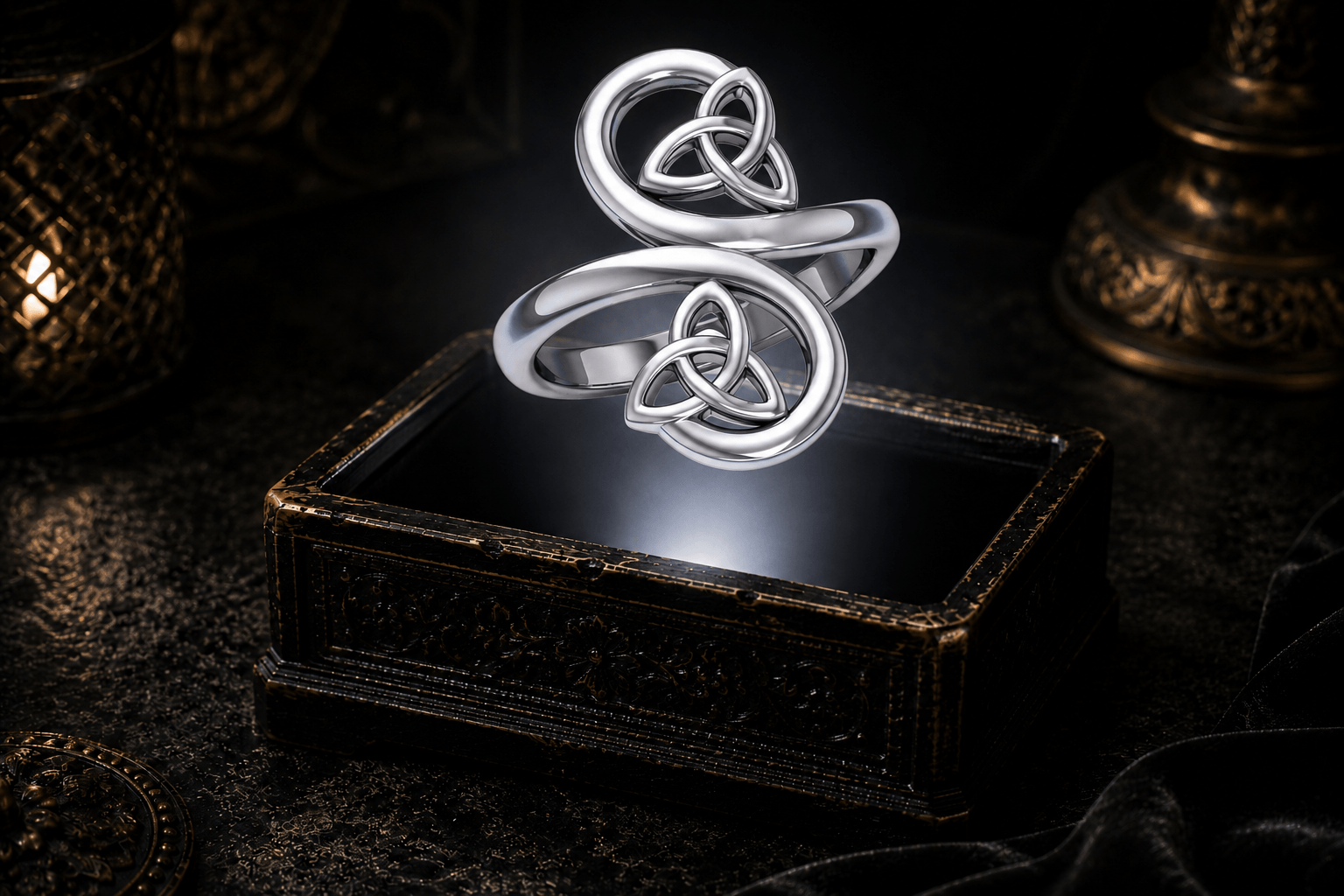 Sterling silver double Trinity knot ring floating above an antique jewelry box within a neutral white beam of light.