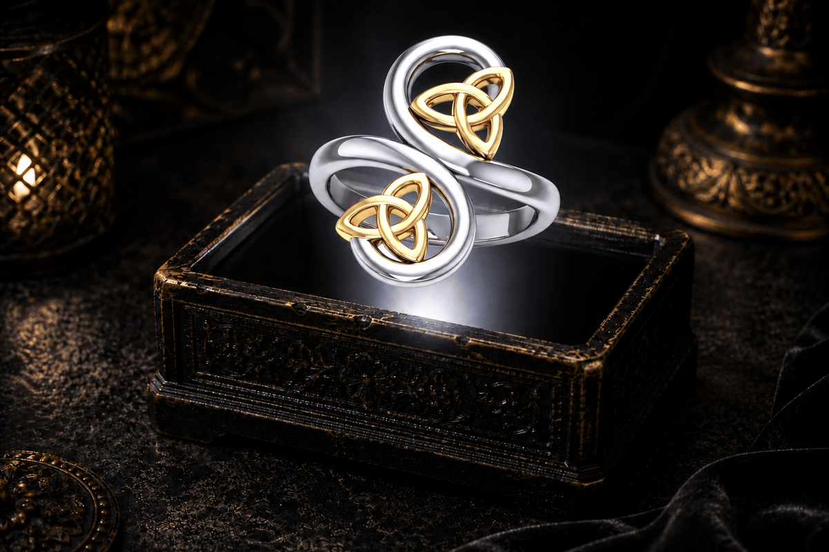 Celtic double Trinity knot ring in .925 sterling silver with two 14K gold Trinity knot accents, floating above an ornate black jewelry box.