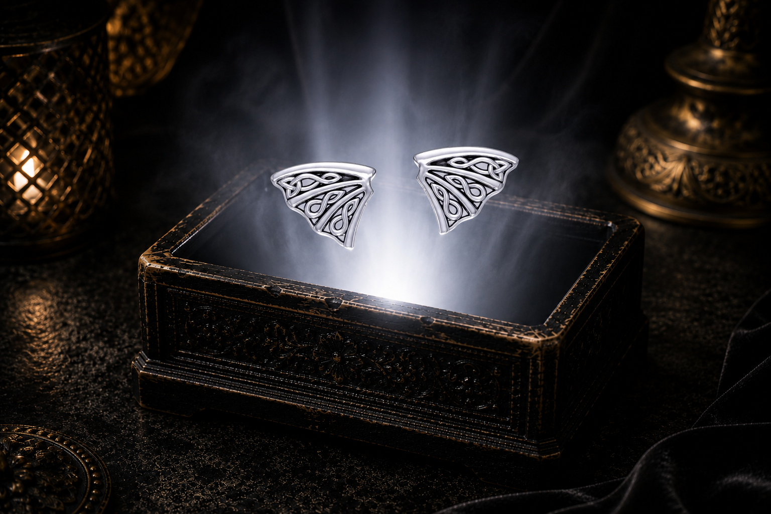 Detailed sterling silver dragon wing earrings with flowing Celtic knotwork showcased above a glowing ornamental jewelry box in an elegant mythic luxury environment.