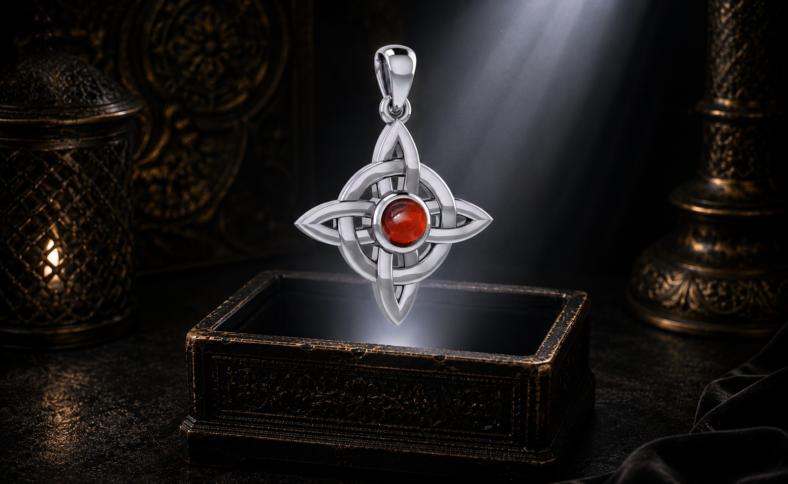 Sterling silver Celtic Four Point Knot Wheel pendant with garnet gemstone suspended above an ornate jewelry box surrounded by warm glowing light in a dark luxury Celtic setting.