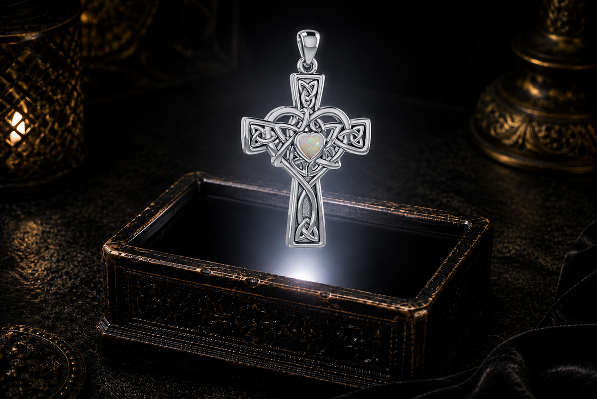 Sterling silver Celtic Heart Cross pendant with a heart-shaped Created Opal gemstone suspended in a luminous beam above an open keepsake box.