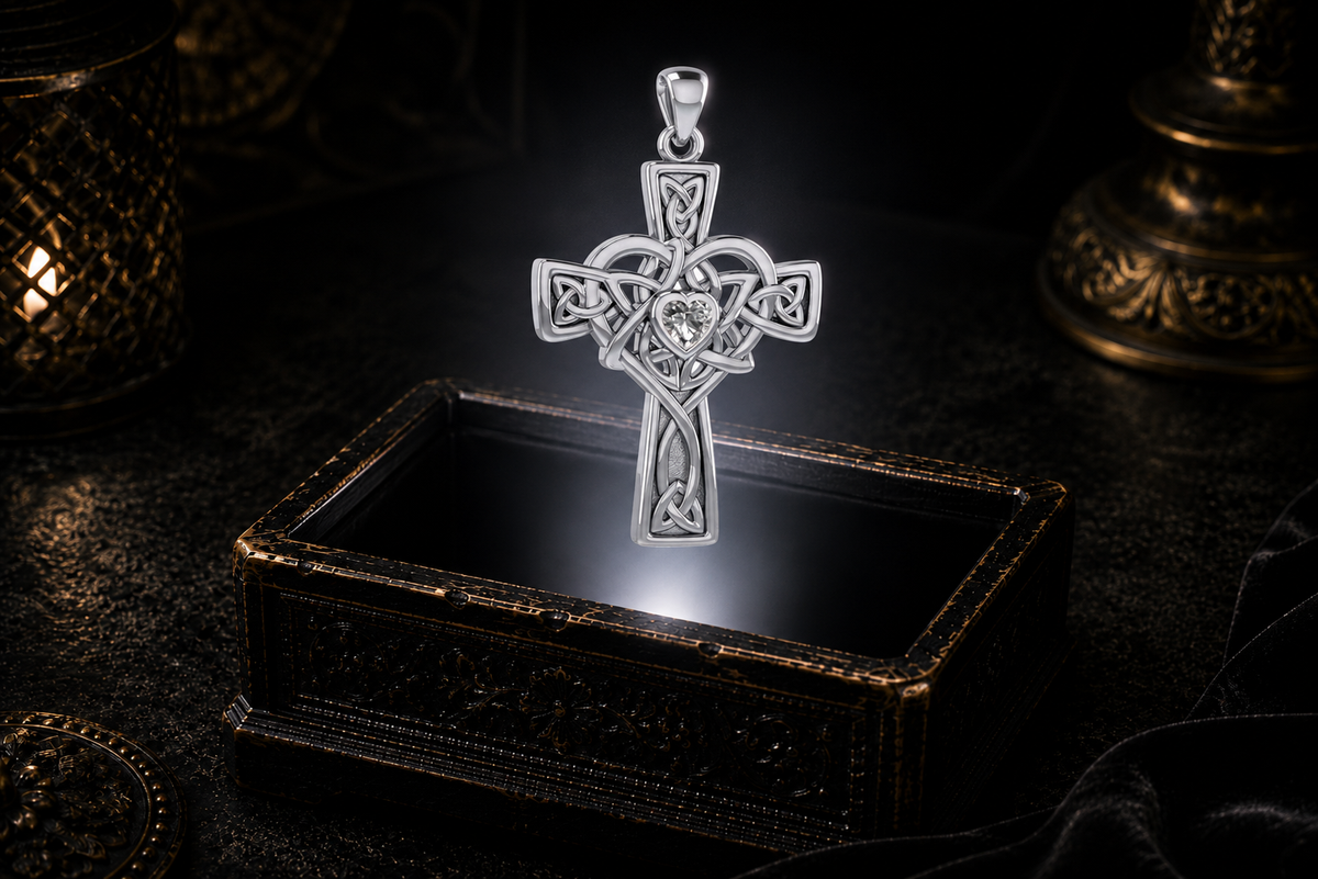 Sterling silver Celtic Heart Cross pendant with a heart-shaped Cubic Zirconia gemstone presented above an antique jewelry box in a cinematic luxury setting.