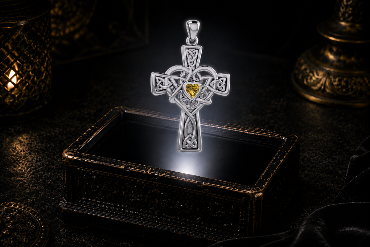 Sterling silver Celtic Heart Cross pendant with a heart-shaped Genuine Citrine gemstone highlighted by soft candlelight over an ornate jewelry box.