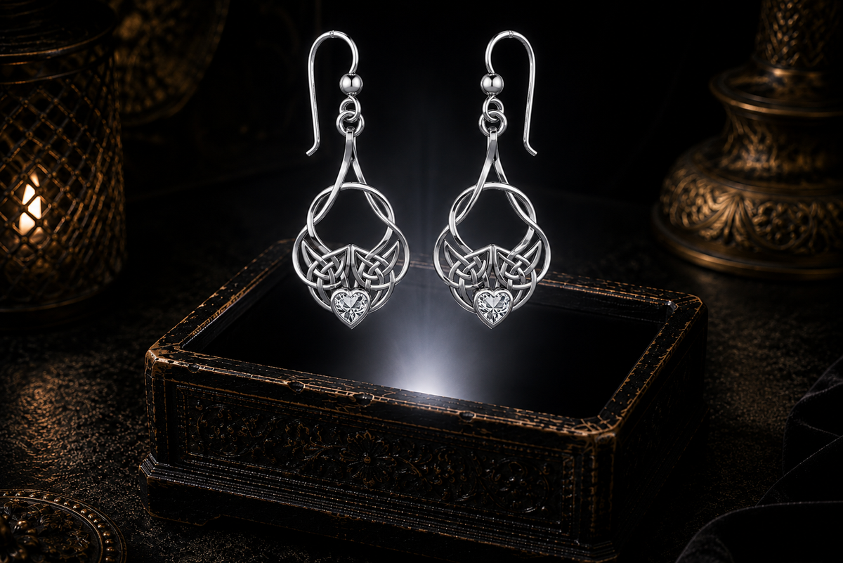 Sterling silver Celtic heart knot earrings with cubic zirconia heart gemstones floating above a glowing ornate jewelry box in a dark luxurious mystical setting