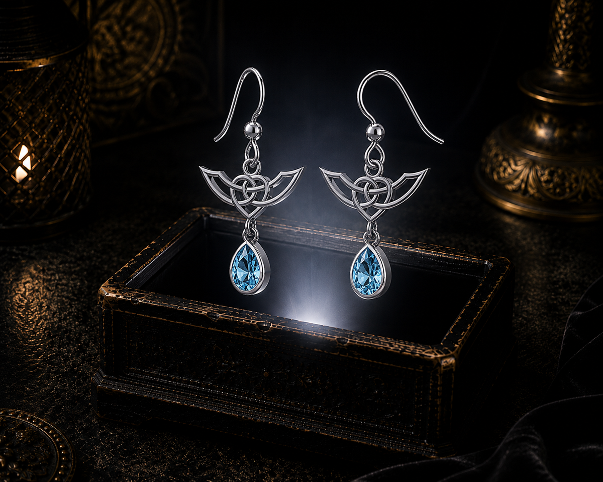 Sterling silver Celtic Infinity Knot earrings with dangling blue topaz gemstones floating above a glowing ornate jewelry box in a dark luxurious mystical setting with cinematic lighting