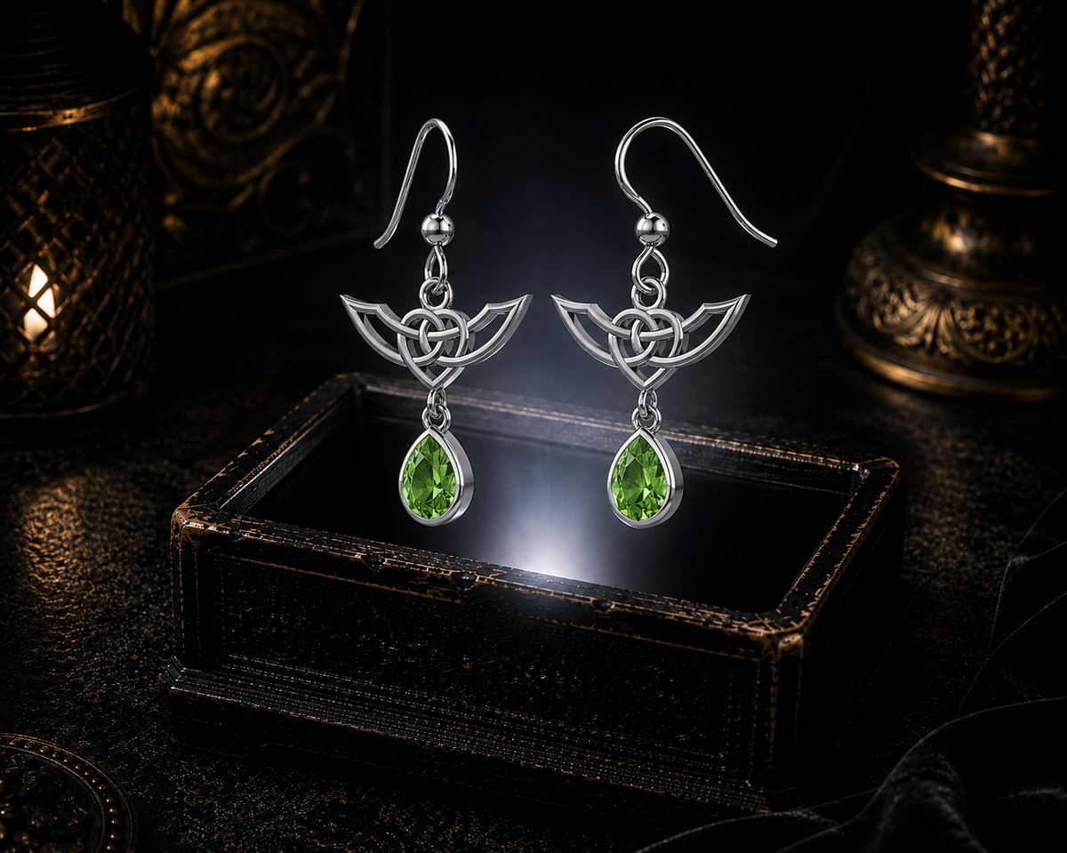 Sterling silver Celtic Infinity Knot earrings with dangling emerald glass gemstones floating above a glowing ornate jewelry box in a dark luxurious mystical setting with cinematic lighting