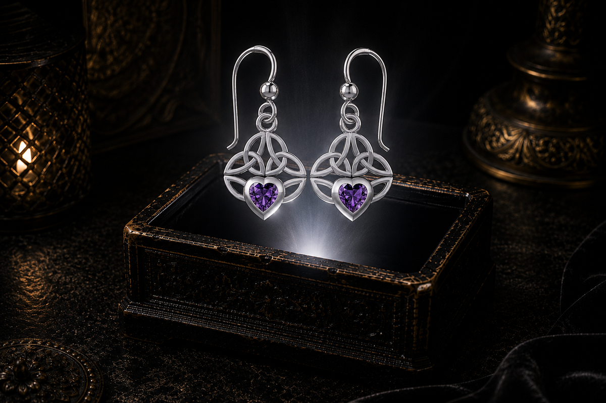 Sterling silver Celtic knot earrings with amethyst heart gemstones floating above a glowing ornate jewelry box in a dark luxury setting