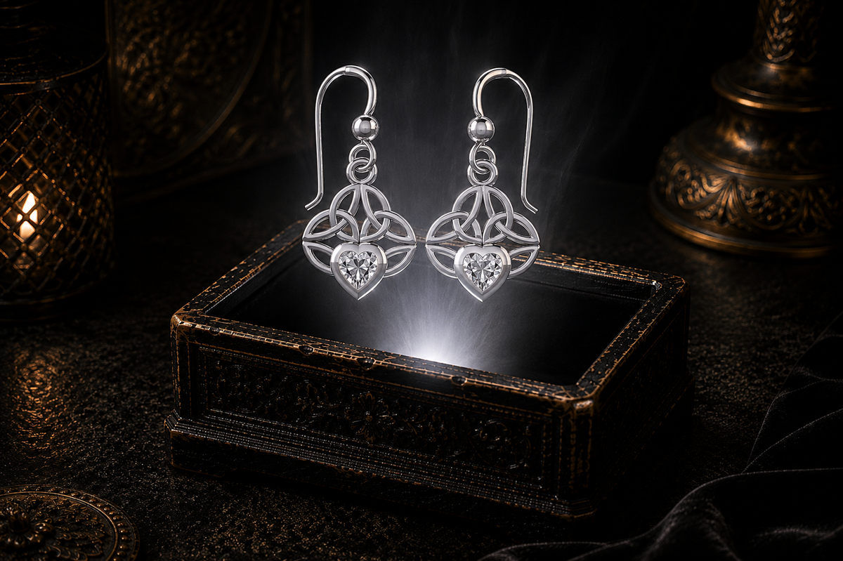 Sterling silver Celtic knot earrings with cubic zirconia heart gemstones floating above a glowing ornate jewelry box in a dark luxury setting