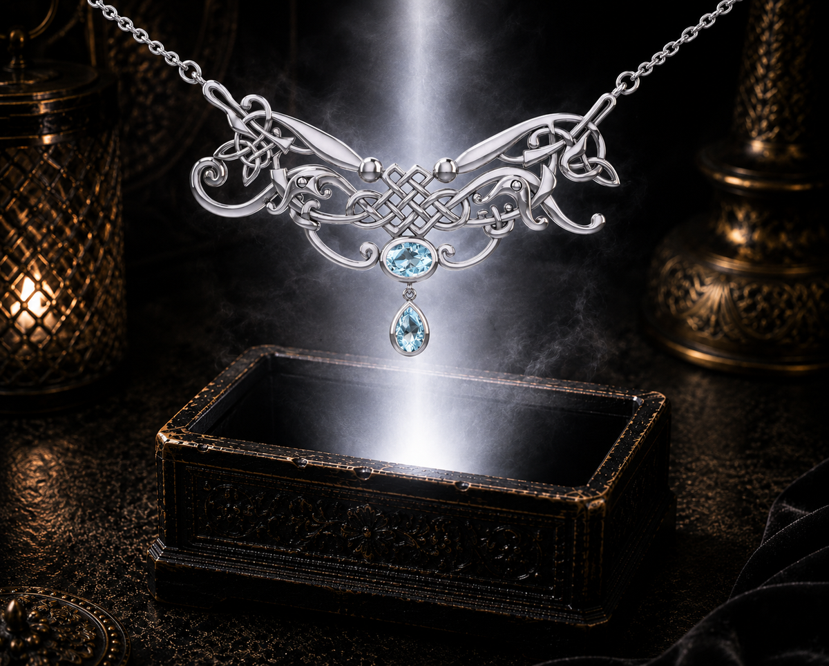 Sterling silver Celtic knotwork filigree necklace with blue topaz gemstones displayed above a luminous jewelry chest surrounded by cinematic shadows and elegant reflections.