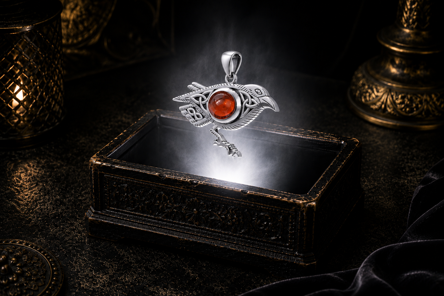 Sterling silver Celtic raven pendant with Triquetra knotwork and garnet gemstone floating above an ornate black jewelry box illuminated by soft white light in a dark luxury setting with candlelight and drifting mist.