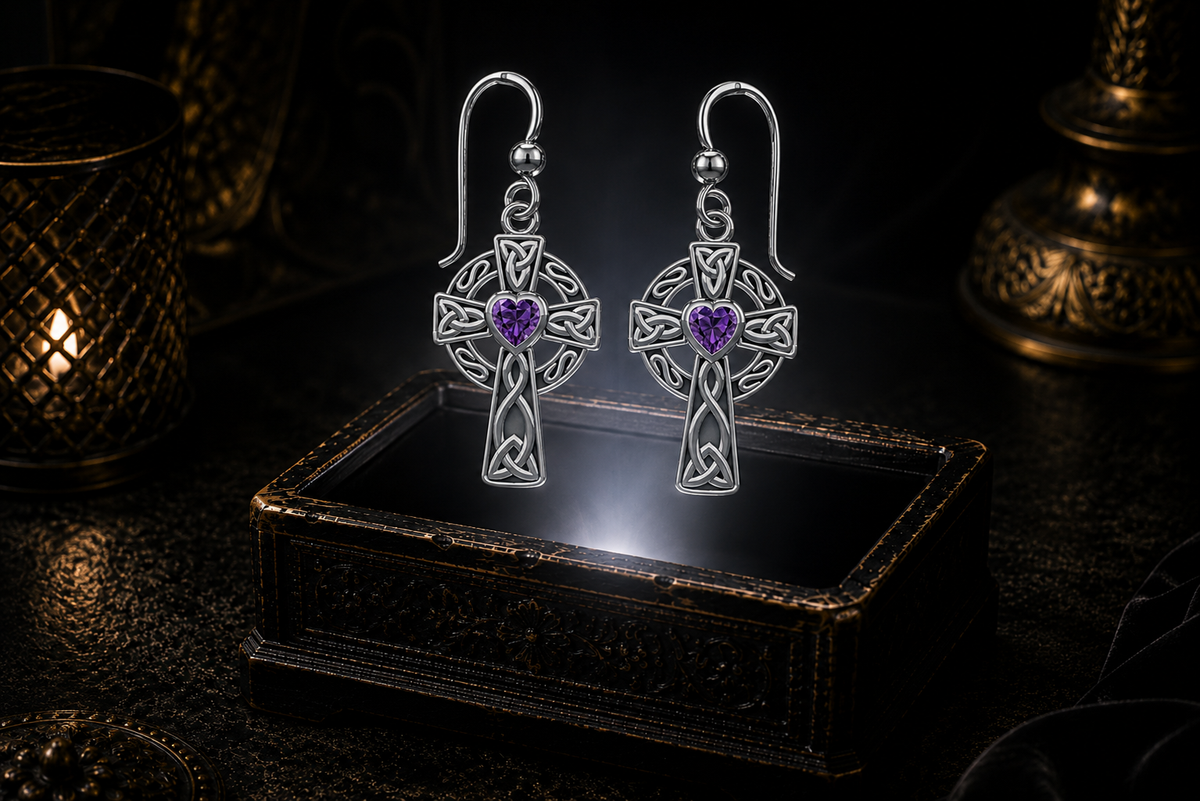 Sterling silver Celtic ringed cross earrings with amethyst heart gemstones floating above a glowing ornate jewelry box in a dark luxury setting