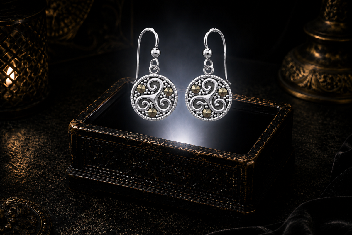 Sterling silver Celtic triskele earrings with marcasite accents floating above a glowing ornate jewelry box in a dark luxury setting