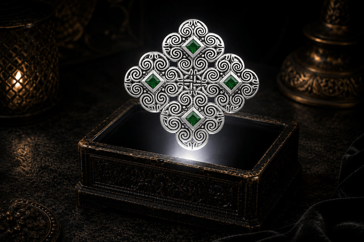 Sterling silver Celtic spiral Triskelia pendant with four square emerald green stones and open scrollwork, floating above an ornate antique jewelry box in a neutral white beam of light