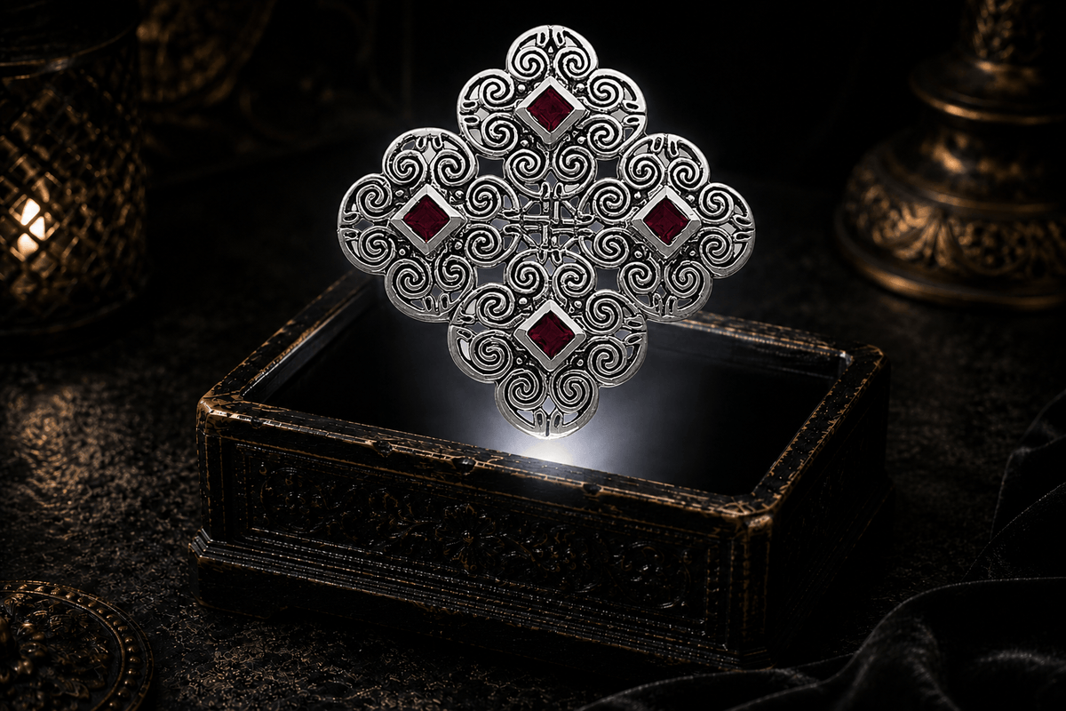 Celtic spiral Triskelia pendant in sterling silver with four square garnet stones set among curling openwork, suspended above an antique jewelry box in a dark atmospheric setting
