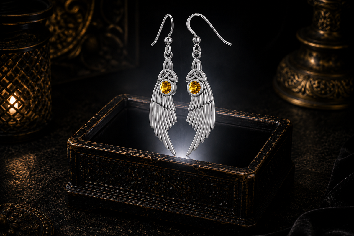 Sterling silver Celtic Trinity Knot angel wing earrings with citrine gemstones floating above a glowing ornate jewelry box in a dark luxurious mystical setting with cinematic lighting