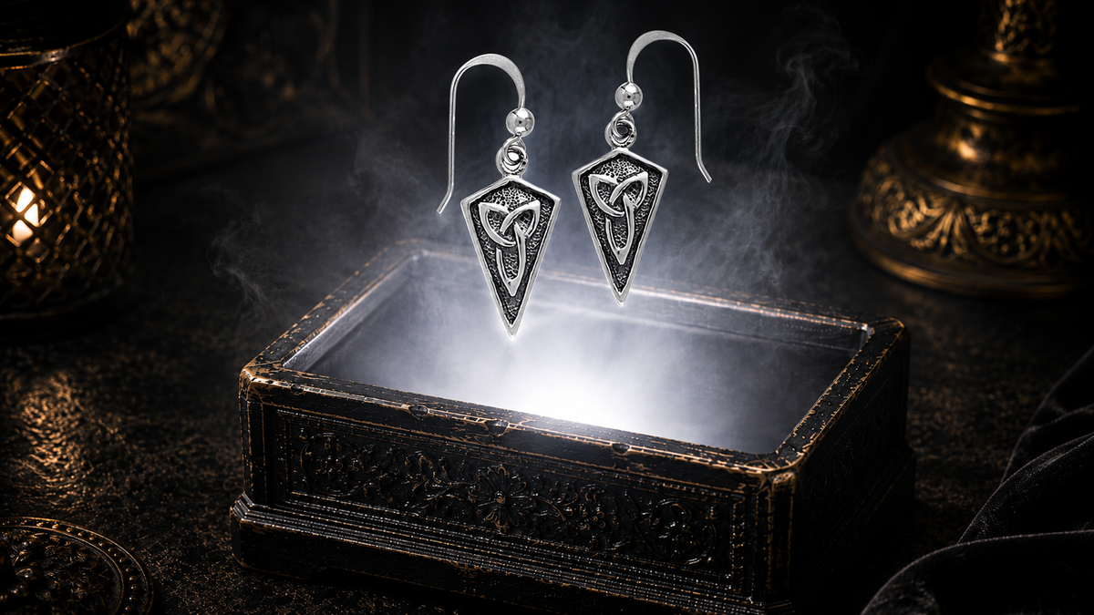 Sterling silver Celtic Trinity Knot earrings featuring the timeless Triquetra symbol floating above an ornate jewelry box in a dark luxury setting with cinematic lighting, mystical atmosphere, and refined Celtic elegance.