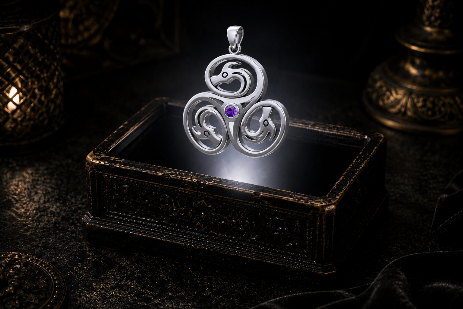 Sterling silver Celtic triple dragon pendant featuring a garnet gemstone suspended within a white beam of light above an ornate keepsake box.