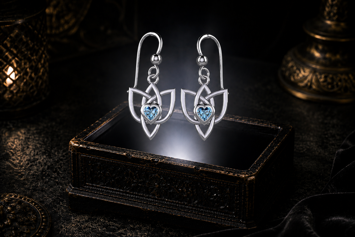 Sterling silver Celtic Triquetra Trinity Knot heart earrings with blue topaz heart gemstones floating above a glowing ornate jewelry box in a dark luxurious mystical setting with cinematic lighting