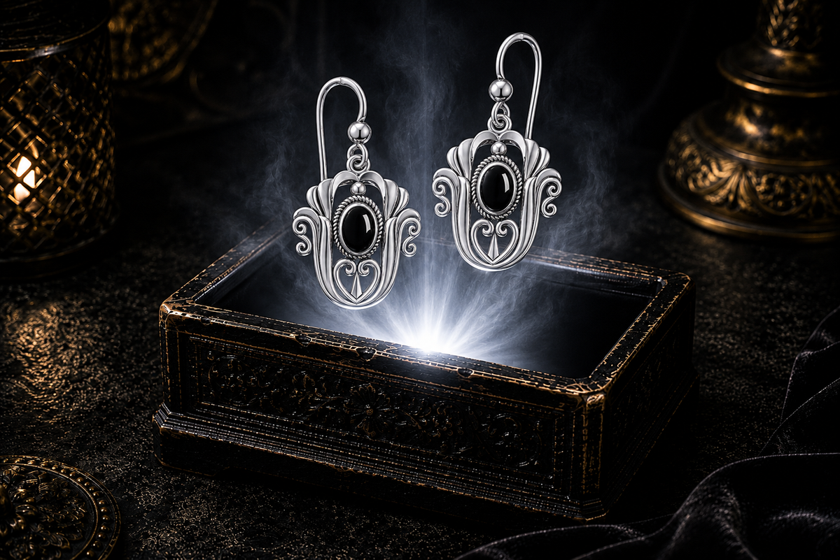 Sterling silver Celtic triquetra tulip earrings with black onyx gemstones floating above a glowing ornate jewelry box in a dark luxury setting